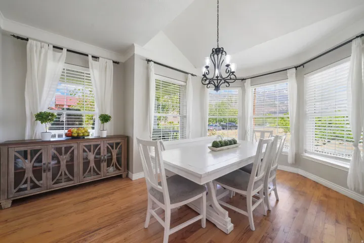 Dining area featuring wood-finish flooring, vaulted ceiling, and an ornate black chandelier