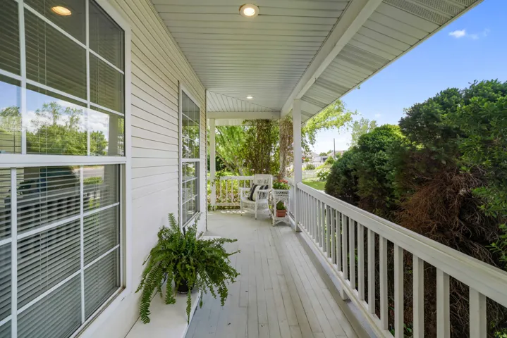 Inviting covered porch with white railing, wood-finish flooring, and recessed lighting
