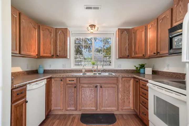 Kitchen featuring wood-finish cabinetry, a double basin sink, and laminate countertops