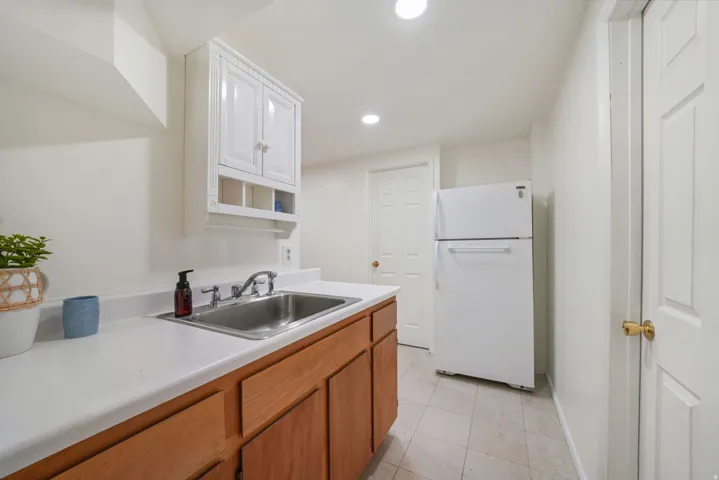 Utility sink with a chrome faucet, white countertop, and light wood-finish cabinetry