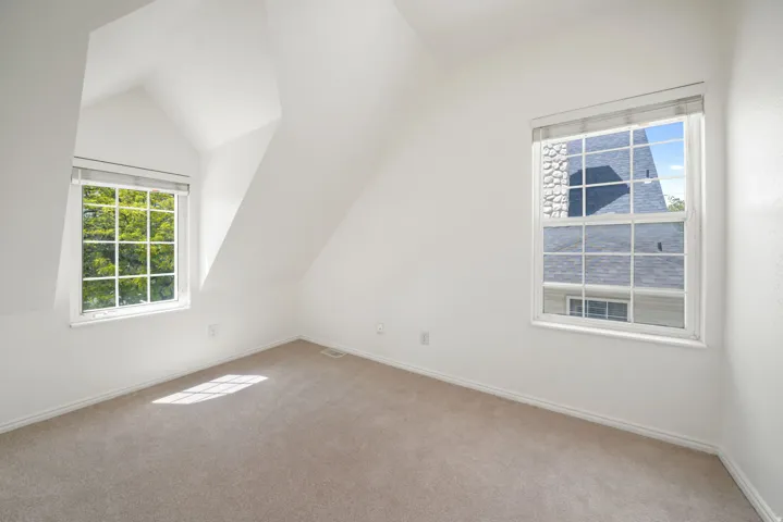 Room with sloped ceilings, neutral carpet, and white walls