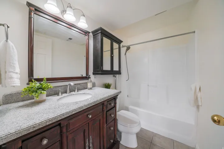 Bathroom vanity featuring a light-toned stone countertop, an undermount sink, and a dark wood-finish cabinet with decorative hardware