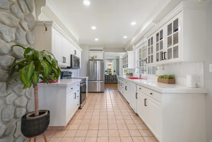 Kitchen featuring white cabinetry, tile countertops, stainless steel appliances, and recessed lighting