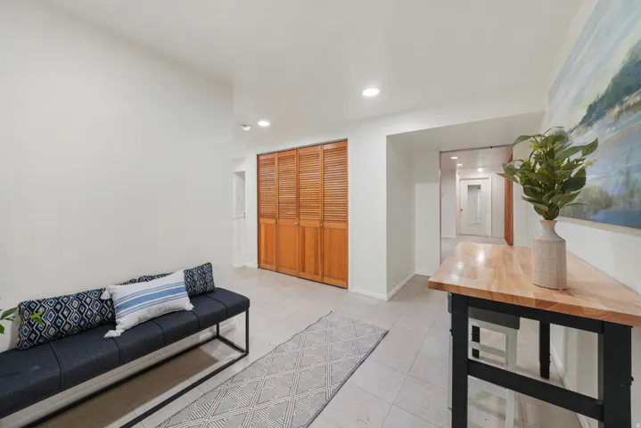 Entryway featuring light tile flooring, white walls, recessed ceiling lighting, and a closet with wood louvered bifold doors