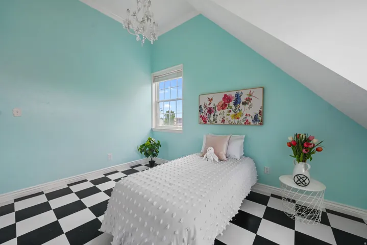 Room featuring an angled ceiling, single window, and distinctive black and white checkerboard flooring