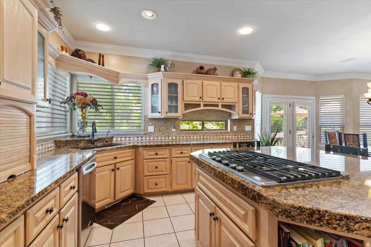 Kitchen featuring light wood cabinetry, granite countertops, tile flooring, recessed lighting, and a built-in gas cooktop on the island