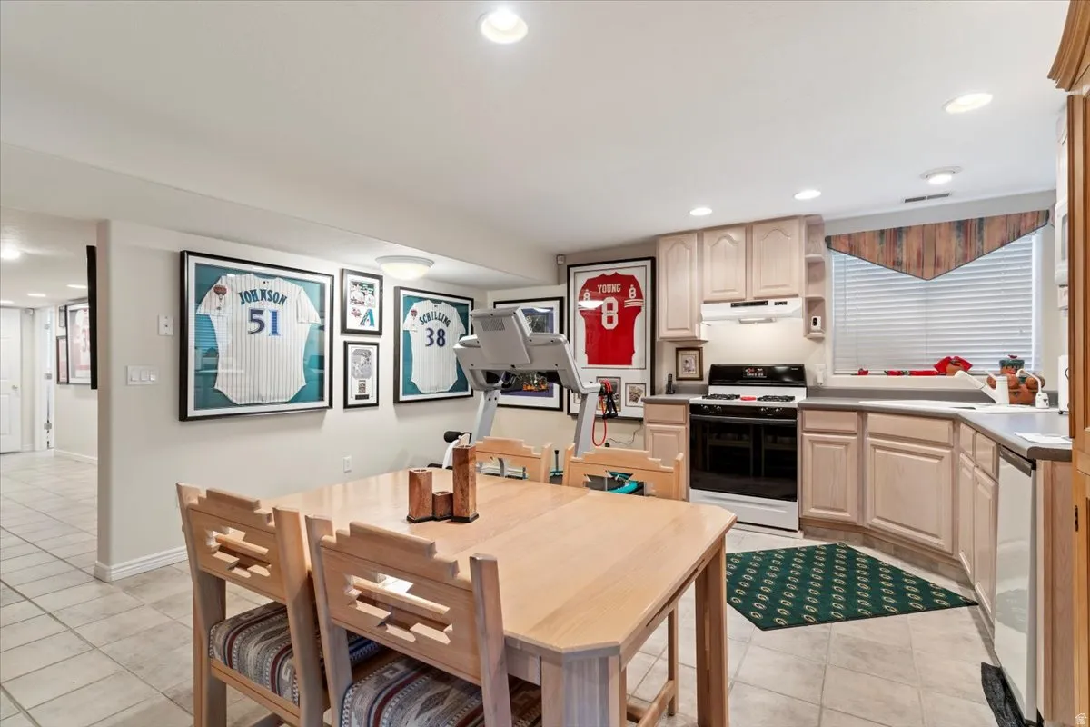 Kitchenette featuring light-toned cabinetry and a white appliance package including a range with an overhead microwave and a dishwasher