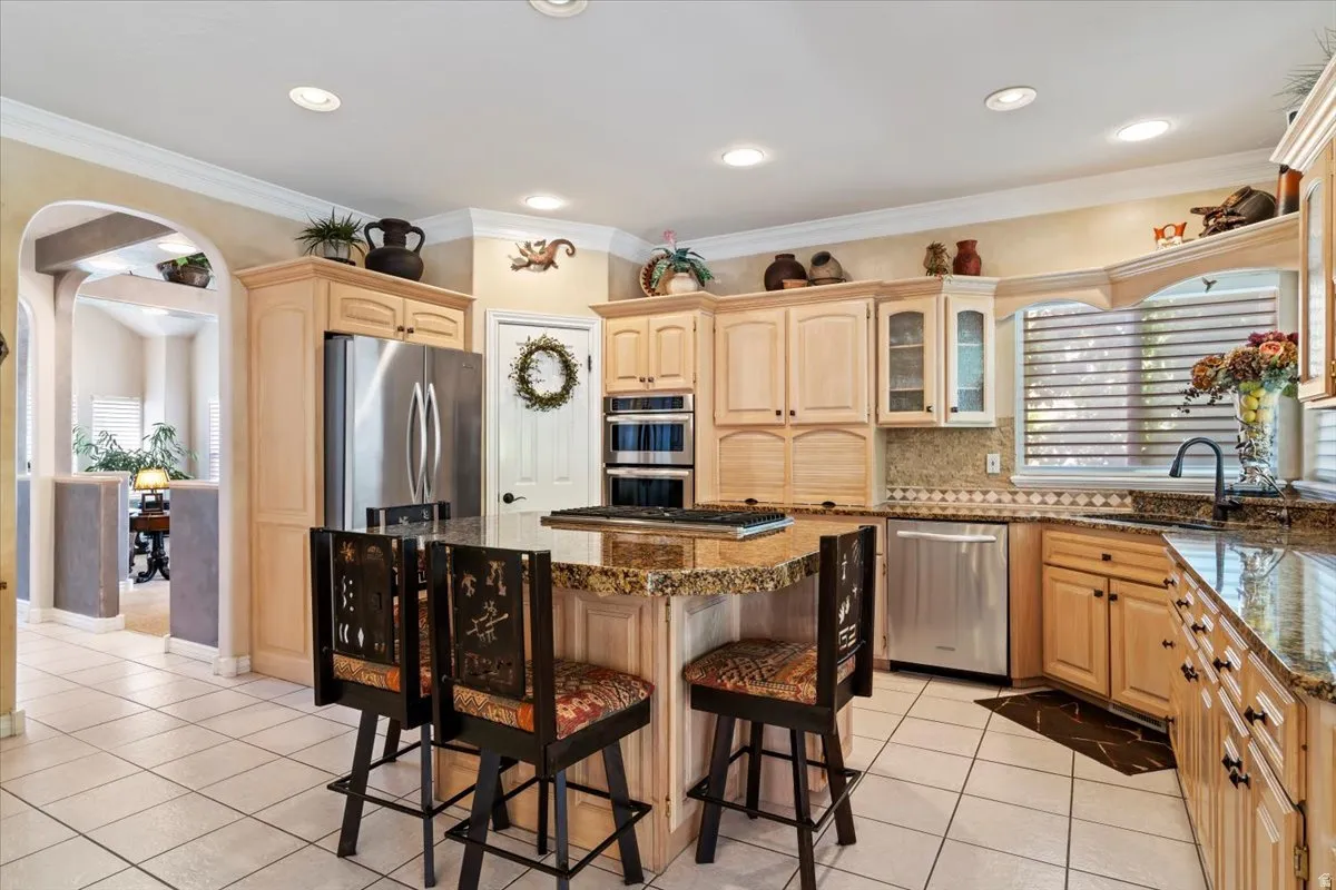 Kitchen featuring light wood cabinetry, granite countertops, and stainless steel appliances including a built-in double oven