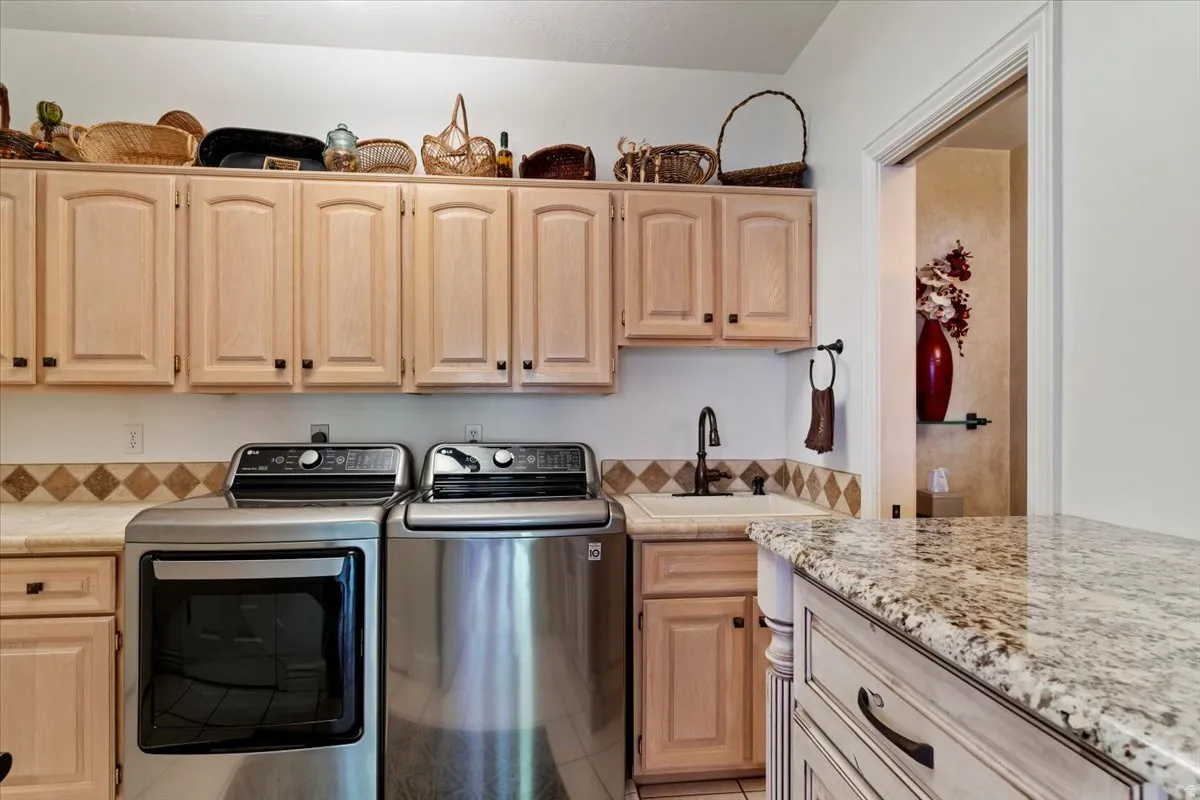 Dedicated utility space featuring extensive light wood-finish cabinetry, a built-in sink with a dark bronze-finish faucet, and granite-style countertops
