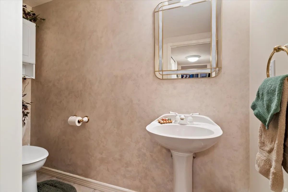 Pedestal sink with white faucet fixtures, framed mirror, and textured wall finish