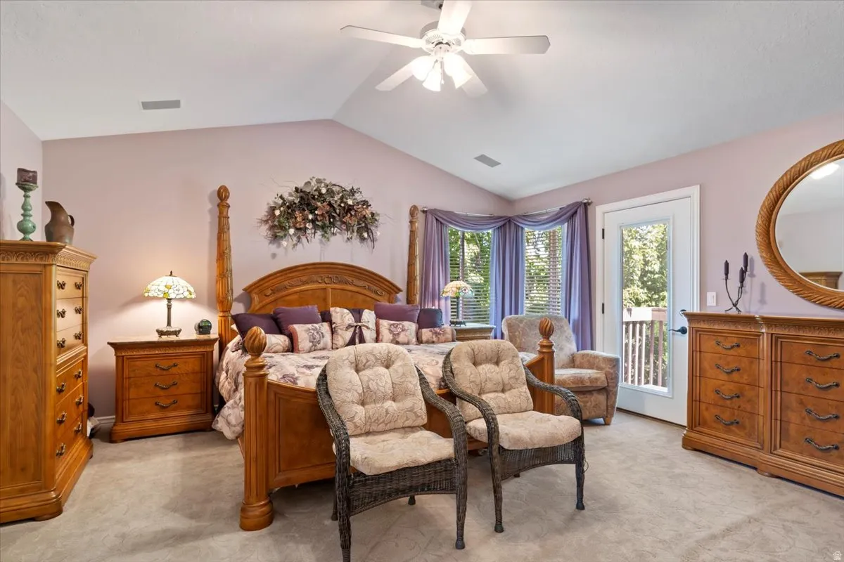 Vaulted ceiling bedroom with a ceiling fan, bay window, and exterior door access to an outdoor area