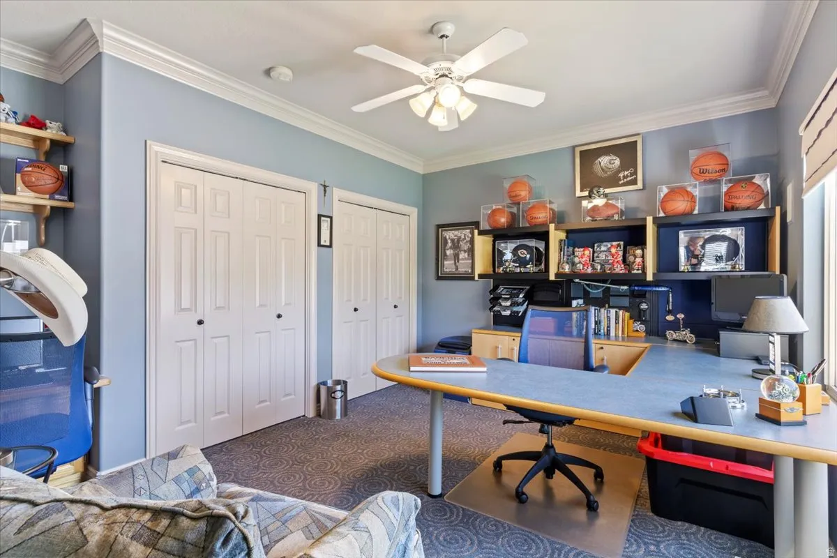 Room featuring two sets of bi-fold closet doors, crown molding, and a ceiling fan