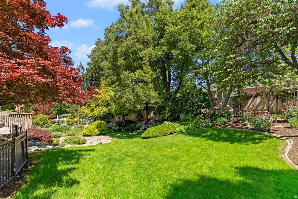 Spacious backyard featuring a manicured lawn, established trees, and diverse landscaping