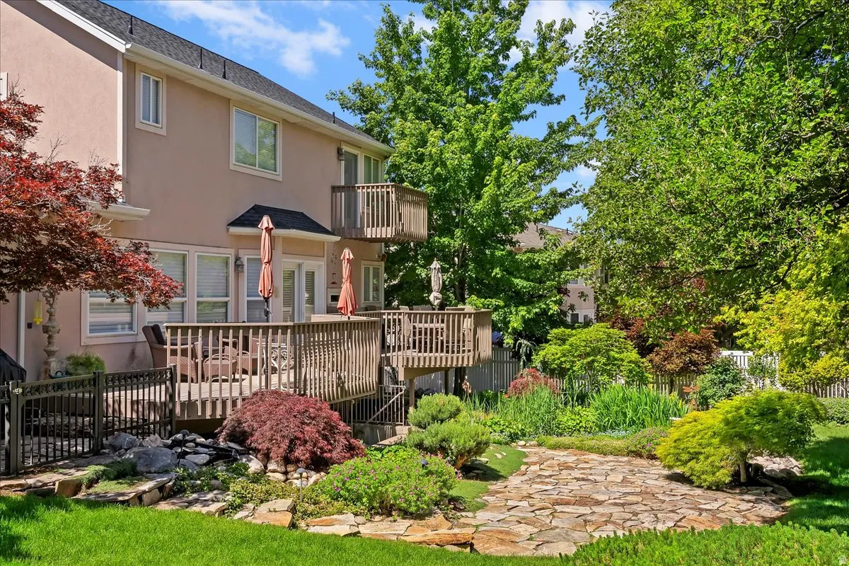 Rear exterior featuring a multi-level wood deck, a second-story balcony, and a manicured lawn