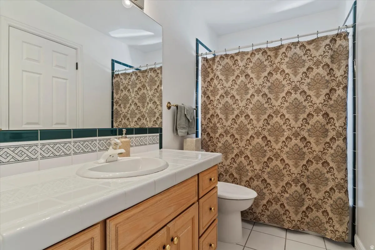 Bathroom featuring a built-in wood vanity with gold-tone hardware, a white tile countertop, and a drop-in sink