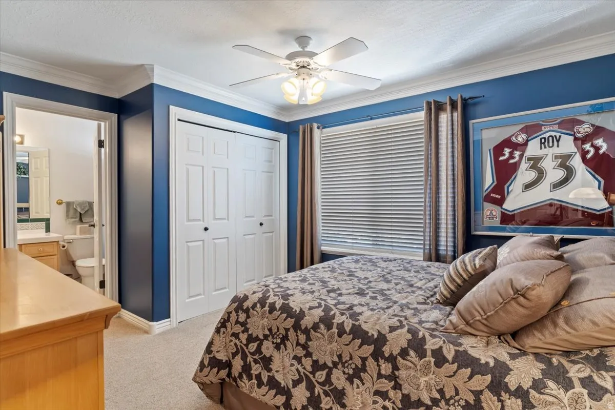 Bedroom featuring blue walls, white crown molding, and a ceiling fan with light fixture