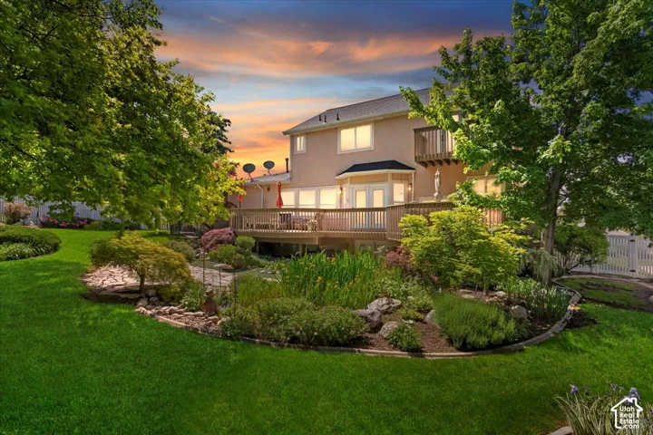 Expansive backyard featuring a manicured lawn, established landscaping, and mature trees