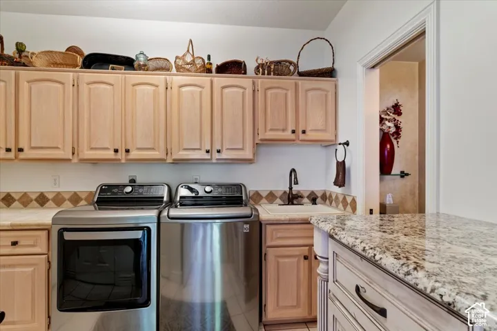 Dedicated utility space featuring extensive light wood-finish cabinetry, a built-in sink with a dark bronze-finish faucet, and granite-style countertops