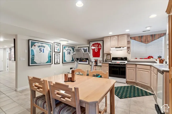 Kitchenette featuring light-toned cabinetry and a white appliance package including a range with an overhead microwave and a dishwasher