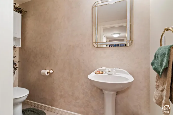 Pedestal sink with white faucet fixtures, framed mirror, and textured wall finish