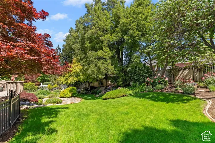 Spacious backyard featuring a manicured lawn, established trees, and diverse landscaping