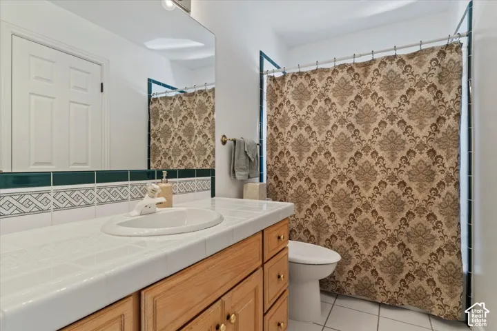 Bathroom featuring a built-in wood vanity with gold-tone hardware, a white tile countertop, and a drop-in sink