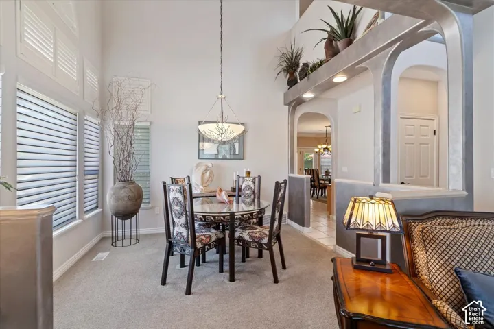 Formal dining area featuring vaulted ceilings, a contemporary chandelier, and large windows with plantation shutters