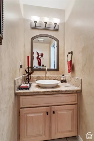 Vanity featuring a vessel sink, tile countertop, and tile backsplash