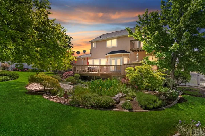 Expansive backyard featuring a manicured lawn, established landscaping, and mature trees