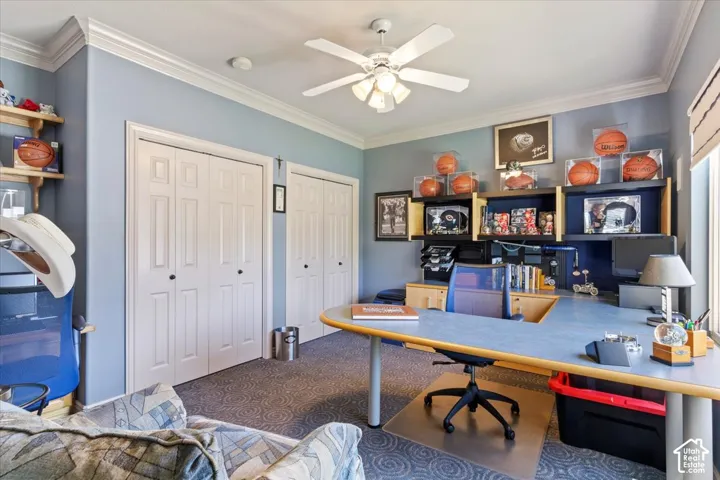 Room featuring two sets of bi-fold closet doors, crown molding, and a ceiling fan