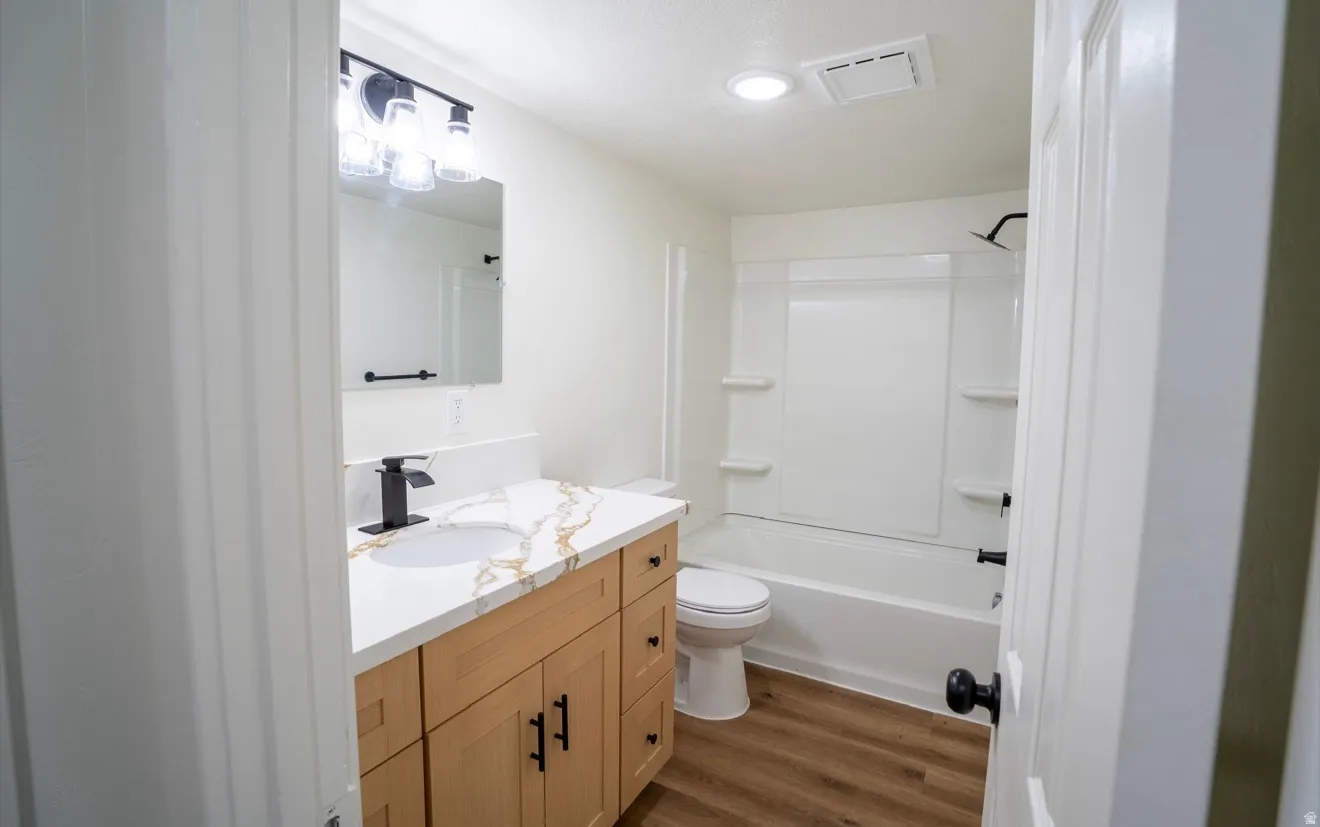 Bathroom featuring a light wood-finish vanity with a quartz-finish countertop and integrated sink