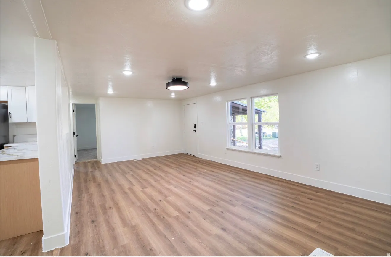 Spacious interior featuring wood-finish flooring, white walls, and recessed ceiling lighting