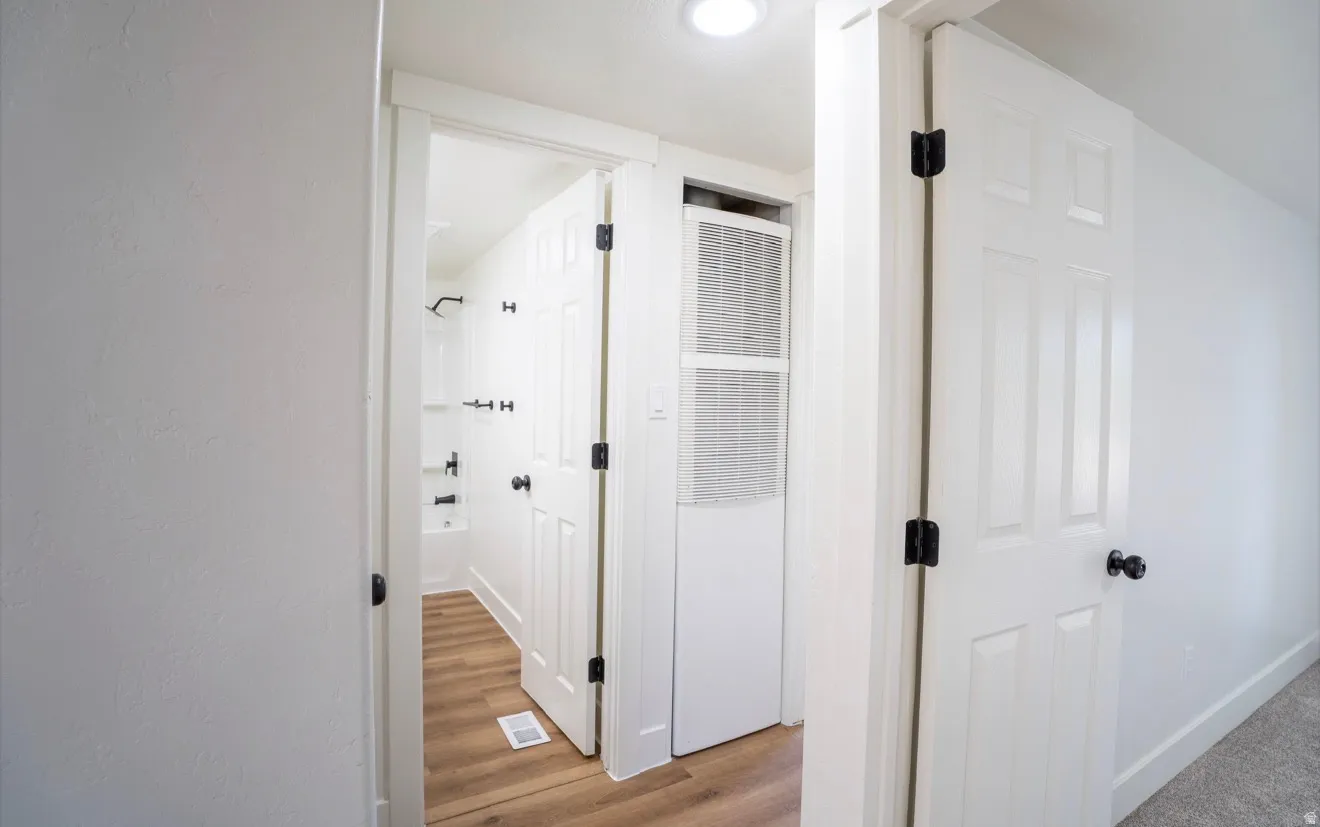 White paneled interior doors with black hardware, wood-finish flooring, recessed lighting, and a white bathtub with black fixtures