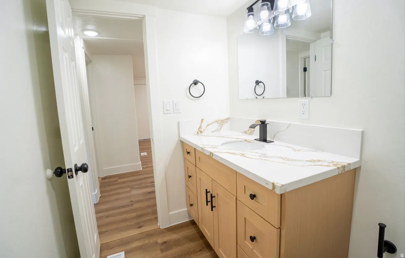 Bathroom vanity with a white countertop featuring gold-toned veining, an undermount sink, and a matte black faucet