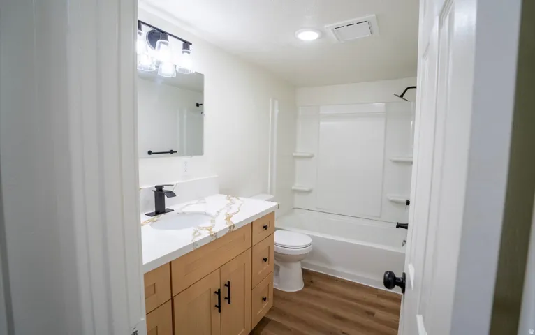 Bathroom featuring a light wood-finish vanity with a quartz-finish countertop and integrated sink