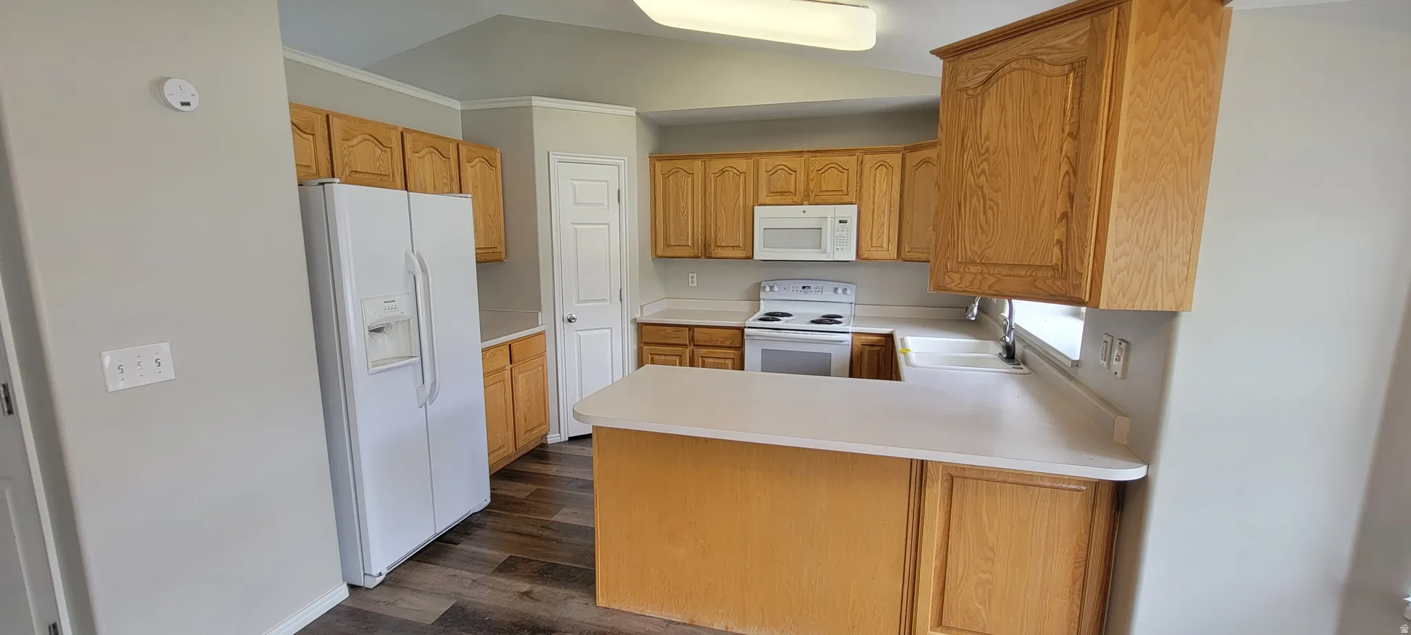 Kitchen featuring wood-finish cabinetry, white countertops, and wood-finish flooring