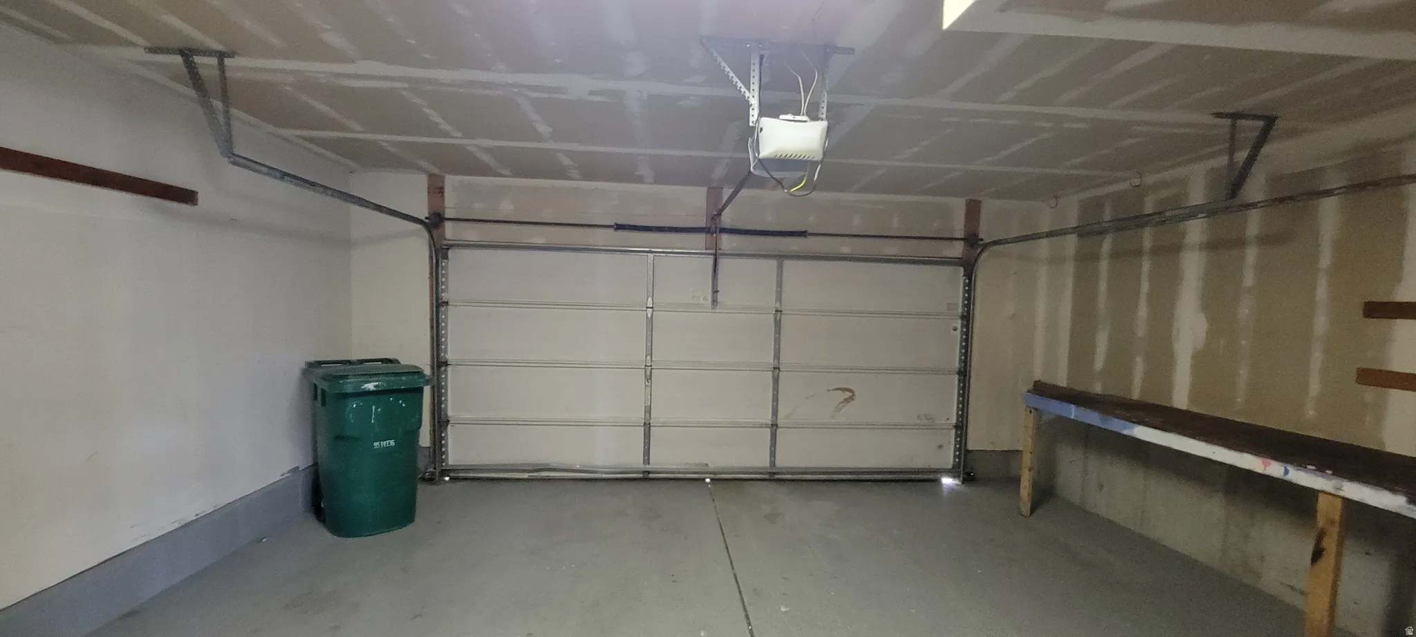 Attached garage featuring a sectional overhead door, exposed ceiling joists, concrete flooring, and an automatic garage door opener