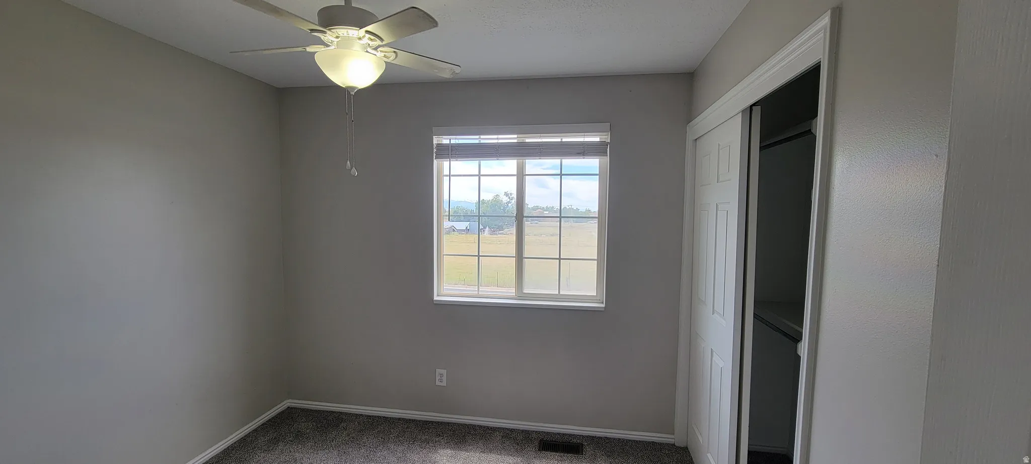 Bedroom featuring neutral wall paint, carpet flooring, a ceiling fan with integrated lighting, a window with horizontal blinds, and a closet with sliding panel doors