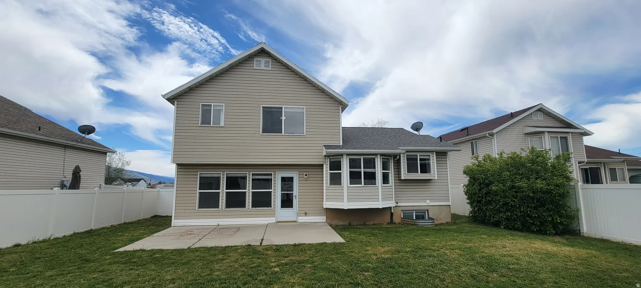 Rear exterior with light beige siding and a sunroom extension