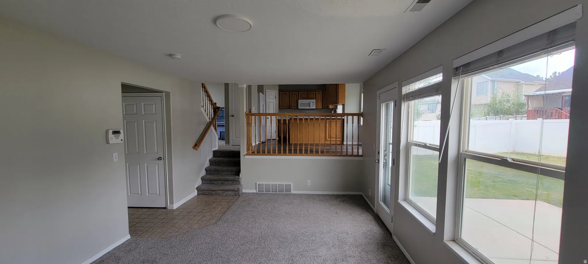 Living space featuring light gray wall tones, new gray carpet, and a white door leading to an additional area