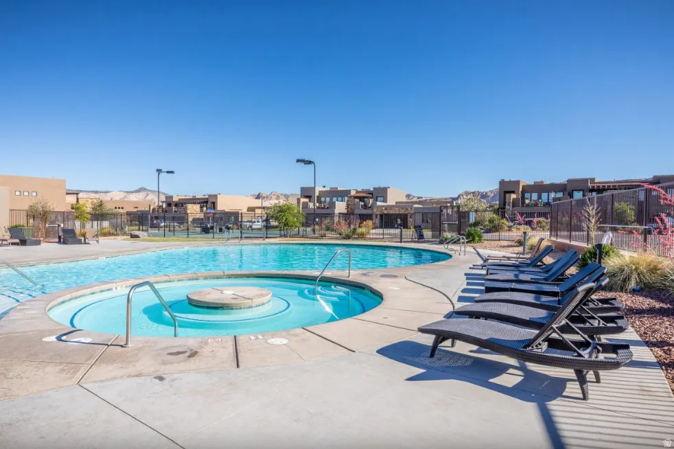 Resort-style pool area featuring a large swimming pool, integrated spa, and concrete deck