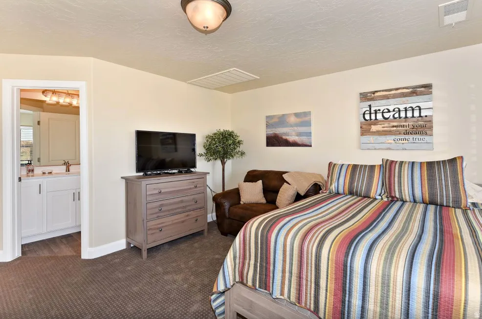 Carpeted bedroom featuring a light fixture, recessed ceiling vent, and neutral wall color