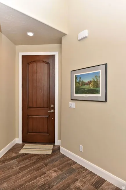 Entryway featuring a rich wood-finish door with an arched panel, diagonal wood-finish flooring, recessed lighting, and white baseboards