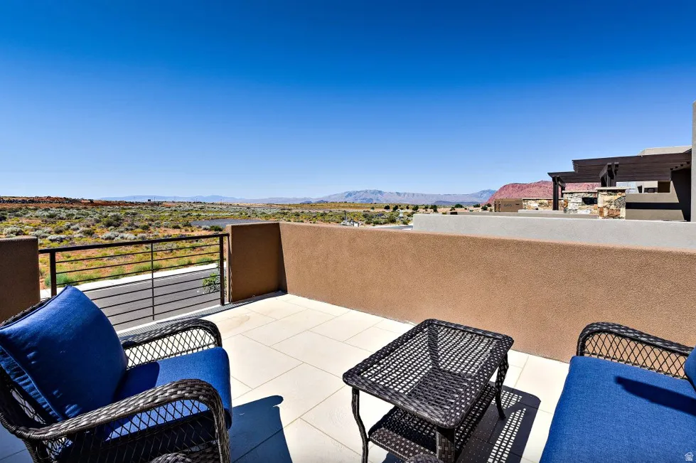 Outdoor patio featuring a tiled surface, stucco walls, and a contemporary metal railing