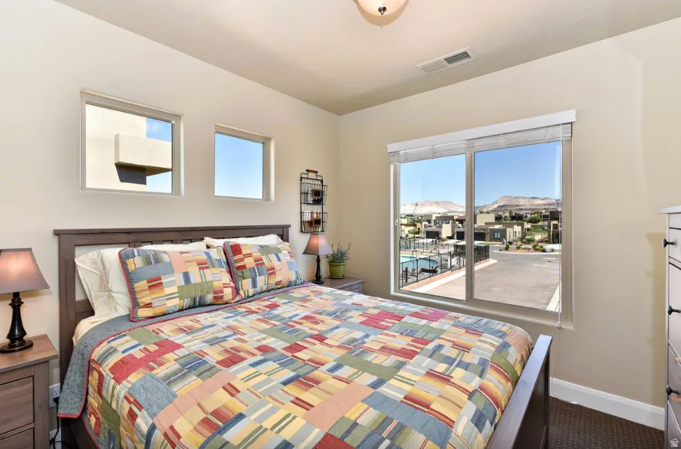 Bedroom featuring a large window with distant mountain scenery and a community pool