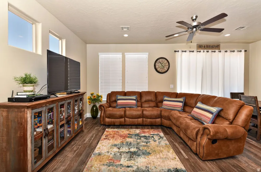 Spacious living area featuring wood-finish flooring, a ceiling fan with integrated lighting, and recessed ceiling lights