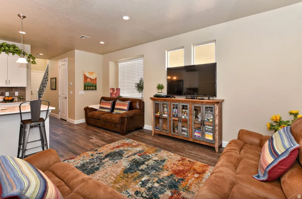 Open-concept living area with wood-finish flooring, recessed lighting, and neutral wall tones