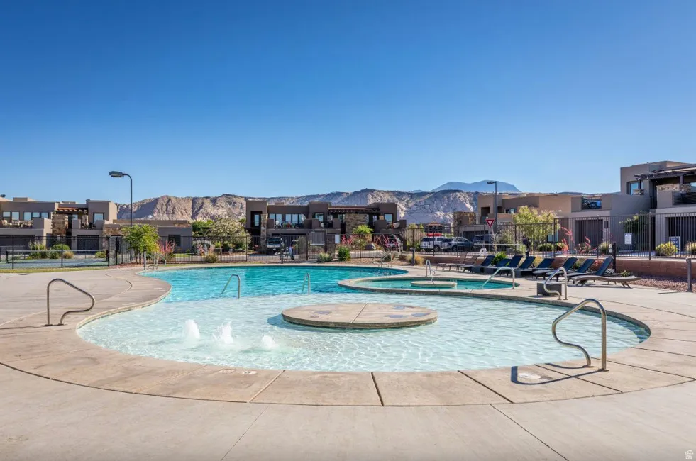 Resort-style pool area featuring multiple swimming zones, integrated water features, and expansive concrete decking