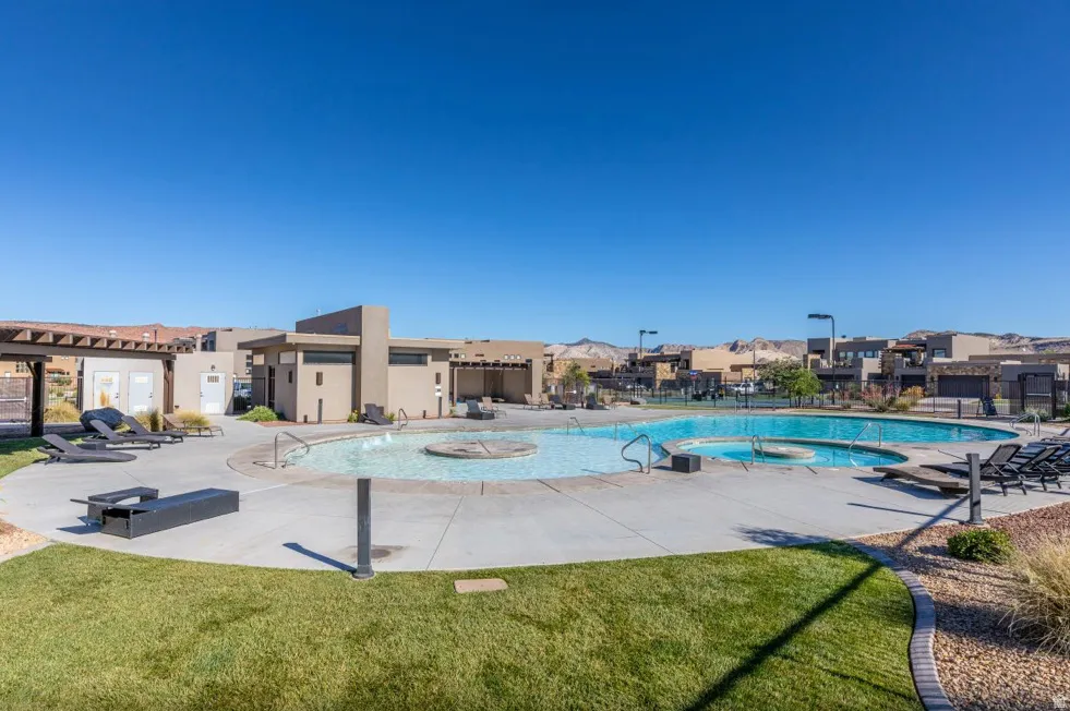 Community swimming pool with an integrated spa, surrounded by a concrete deck and manicured lawn