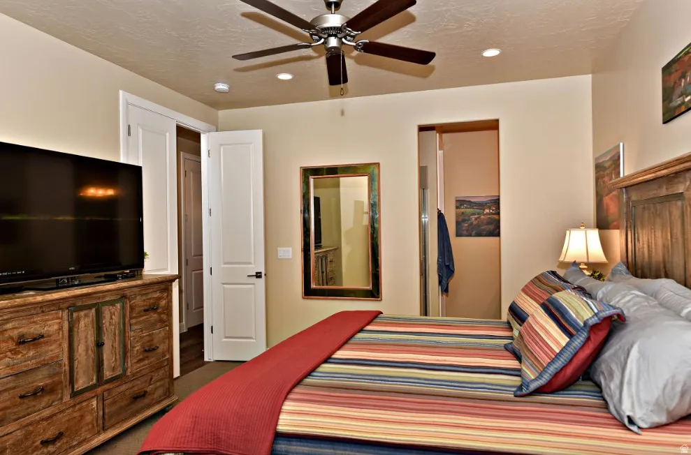 Bedroom featuring a wood-finish bed frame, ceiling fan with integrated lighting, recessed lighting, and a wood-finish dresser